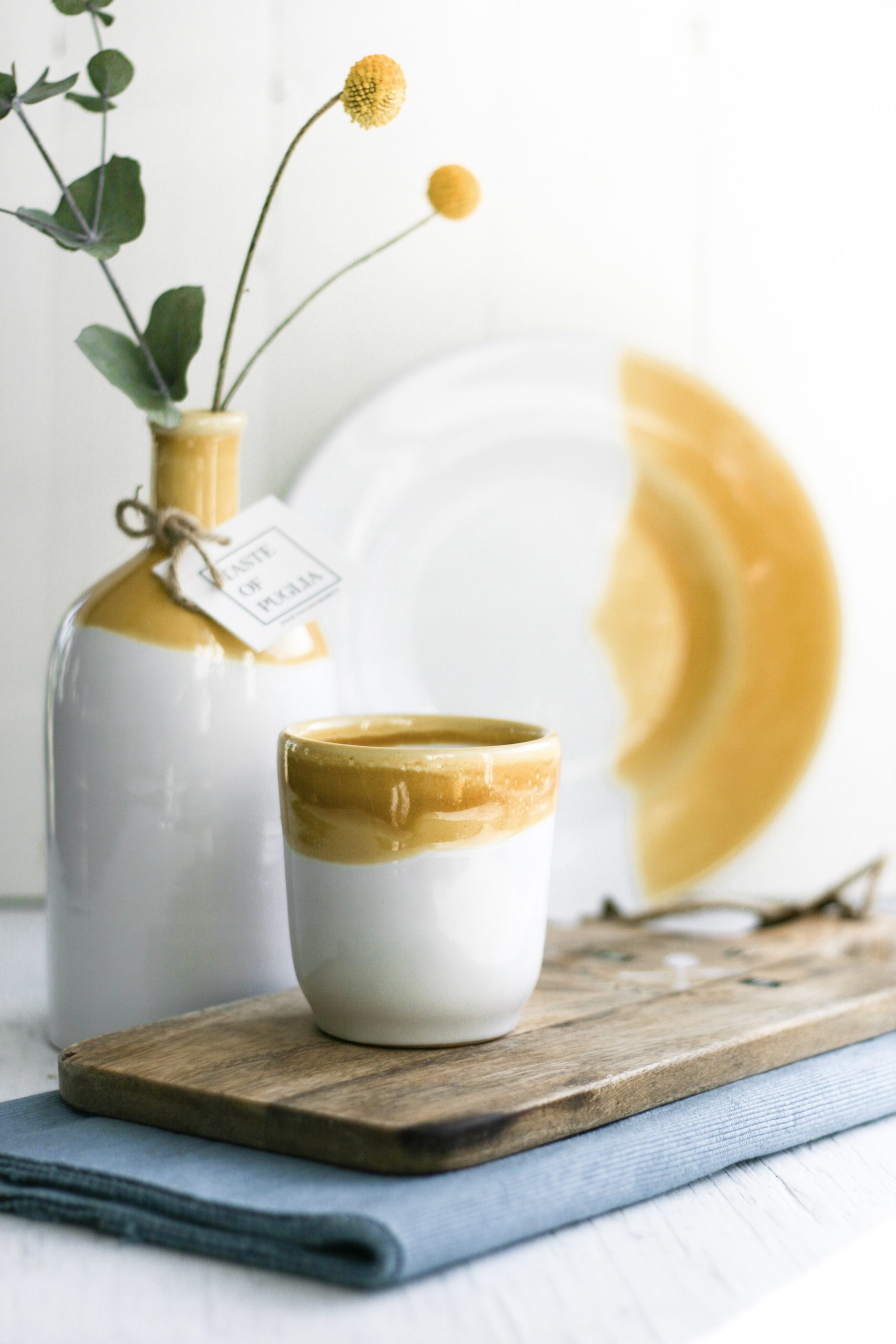 okergeel-italiaans-servies Italiaans koffiekopje op een plank naast een oliefles